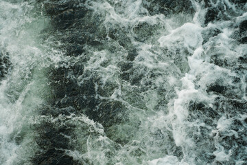 Fototapeta na wymiar Dark water swirling waves and foam texture background