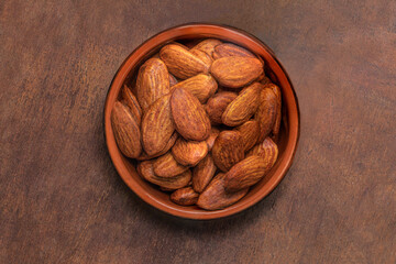  Almonds nuts in a bowl on wooden background. Top view. Copy space
