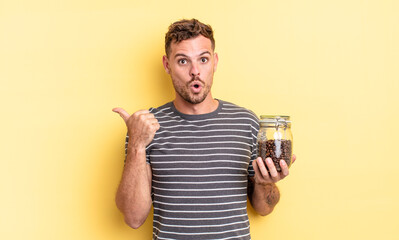 young handsome man looking astonished in disbelief coffee beans concept