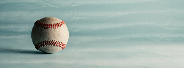 Used game ball shows old baseball on blue texture banner background with copy space for sport.