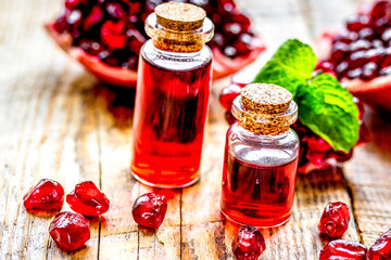 sliced pomegranate and extract in glass on wooden background