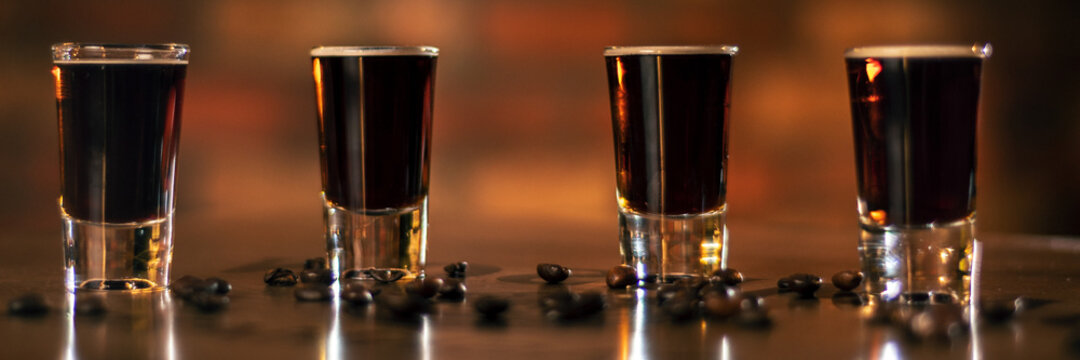 four alcohol coffee shot and coffee beans on the wooden table panorama