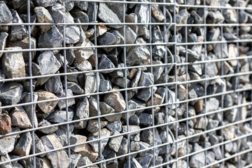 Small granite stones behind a metal mesh, design fence, garden concept