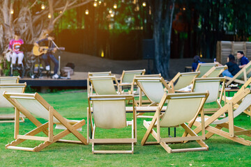 Many white deck chairs with tables for dinner in lawn is surrounded by shady green grass with...
