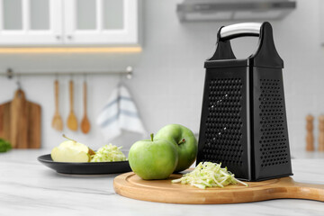 Grater and fresh ripe apples on white table in kitchen. Space for text