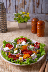 Warm salad with pumpkin, feta cheese, sun-dried tomatoes, olives, arugula and red onion. Close-up.