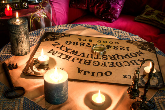 Ouija board on a table with candles. Concept of spiritism on Hallowen