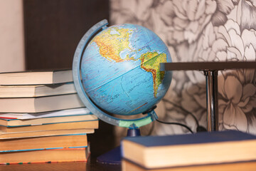 The student's homework table is filled with books and a globe