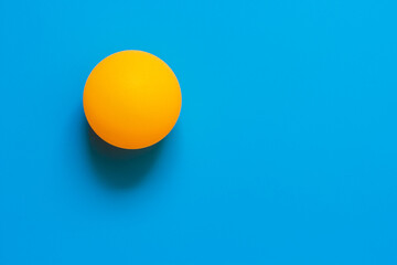 Orange ball table tennis on blue wall background 