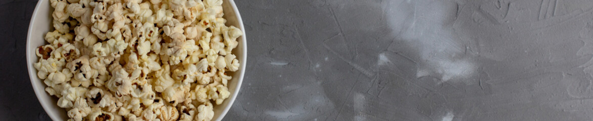 banner of Popcorn in white bowl on grey table. Top view with copyspace