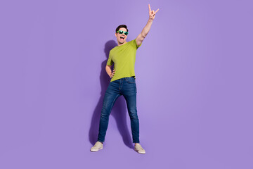 Photo of sweet funky young guy dressed green t-shirt dark eyewear smiling dancing showing rock sign...