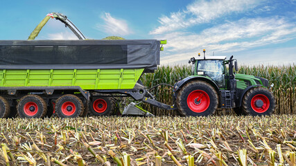 Traktor mit Hänger und Mais Häcksler. Laden des zerhäckselten Mais für die Biogasanlage.
