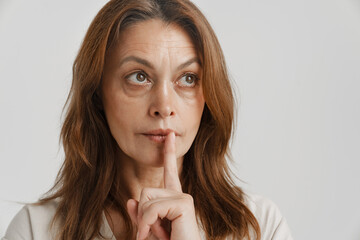 European ginger woman showing silence gesture at camera