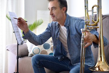 Trombonist making annotations on a sheet music practicing at home