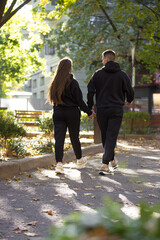 Fototapeta premium Stylish fashionable couple in black costumes walking in the city alley