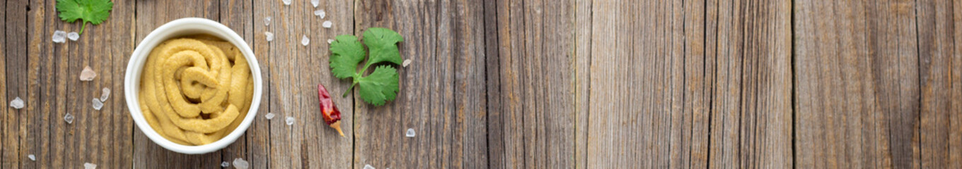 banner of mustard sauce with spices on natural wooden background.