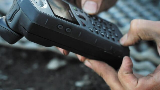 Yukon river, Yukon Territory, Alaska, USA. Night camp of a canoe expedition to Alaska. Close up of hands dialling satellital phone.