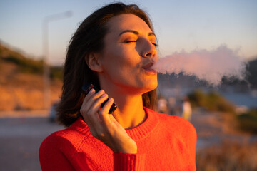 Young woman in a red sweater at a magnificent sunset on the mountain against the background of the...