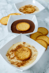 Bowl of custard cream with biscuit and cinnamon