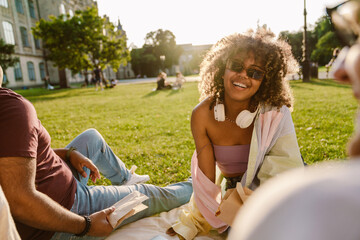 Multiracial students talking and laughing together while resting on grass