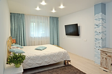 Bedroom interior in light tones with TV on the wall
