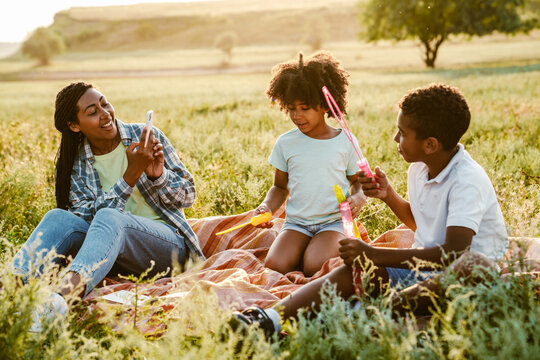 Black mother taking photo of her two son during picnic