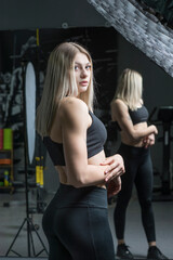 Fototapeta na wymiar Young beautiful blonde girl is engaged in the gym.