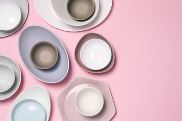 Different plates and bowls on pink background, flat lay. Space for text