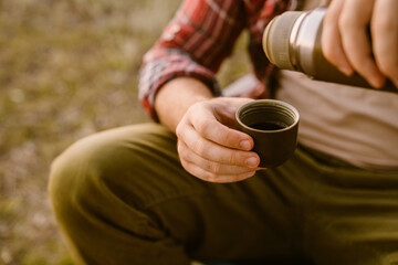 White man drinking tea during camping on summer day