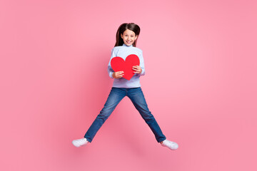 Fototapeta na wymiar Full length body size view of attractive cheerful trendy girl jumping holding heart isolated over pink color background