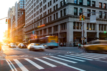 Busy intersection on 5th Avenue and 23rd Street in New York City with rush hour traffic driving...