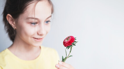 A bee sits on an aster, a teenage girl holds a flower with curiosity in her hands selective focus