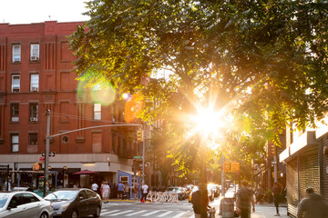 Sunlight shining on the busy intersection on Clinton Street in the Lower East Side neighborhood of...