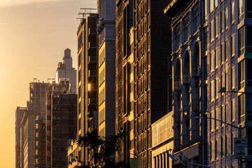 Block of historic buildings in New York City with the warm light of sunset casting long shadows across the windows