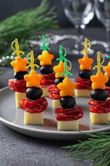 Canapes with cheese, sausage and black olives on a gray plate. Closeup.