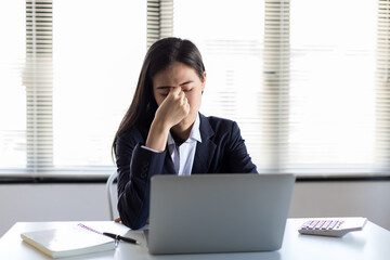 Young Asian business woman work hard with laptop computer and feeling bored or stressed at work in the office. Office syndrome concept