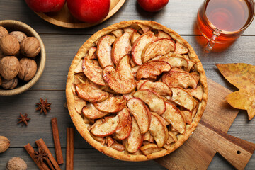 Delicious apple pie, ingredients and cup of tea on wooden table, flat lay