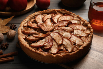 Delicious apple pie, ingredients and cup of tea on wooden table