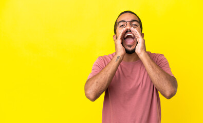 Young latin man isolated on yellow background shouting and announcing something