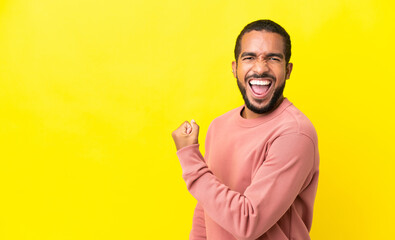 Young latin man isolated on yellow background celebrating a victory