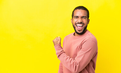 Naklejka premium Young latin man isolated on yellow background celebrating a victory