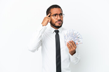 Young business latin man taking a lot of money isolated on white background having doubts and thinking