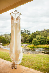Horizontal shot of flesh-colored bridesmaid dress hanging on wood hangers
