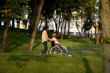 Love couple with wheelchair walking in autumn park