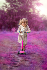 Little girl on a scooter in a fantasy nature