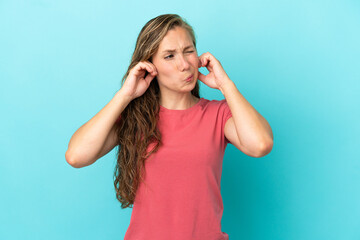Fototapeta premium Young caucasian woman isolated on blue background frustrated and covering ears