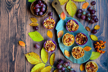 Grapes, apple muffins, yellow foliage on a brown wooden background. View from above