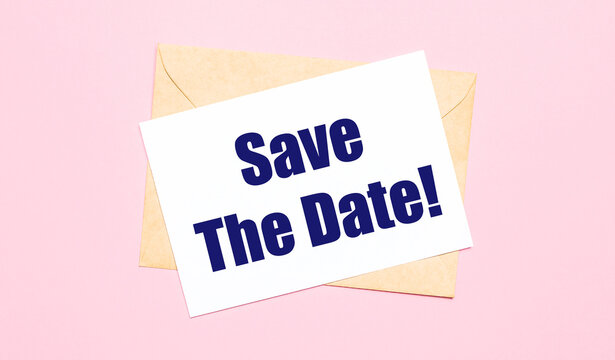 On a light pink background - a craft envelope. It has a white sheet of paper that says SAVE THE DATE