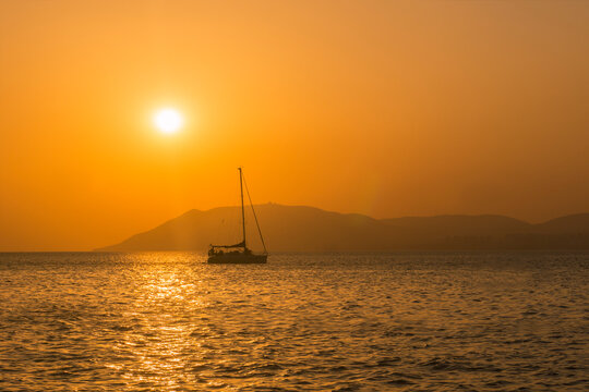 Yacht with lowered sail, sunset against the backdrop of mountains