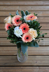 A bouquet of orange, yellow and white flowers in a vase.
